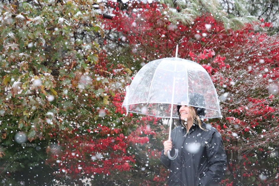 Woman happy to be  in late Fall snow storm with umbrella