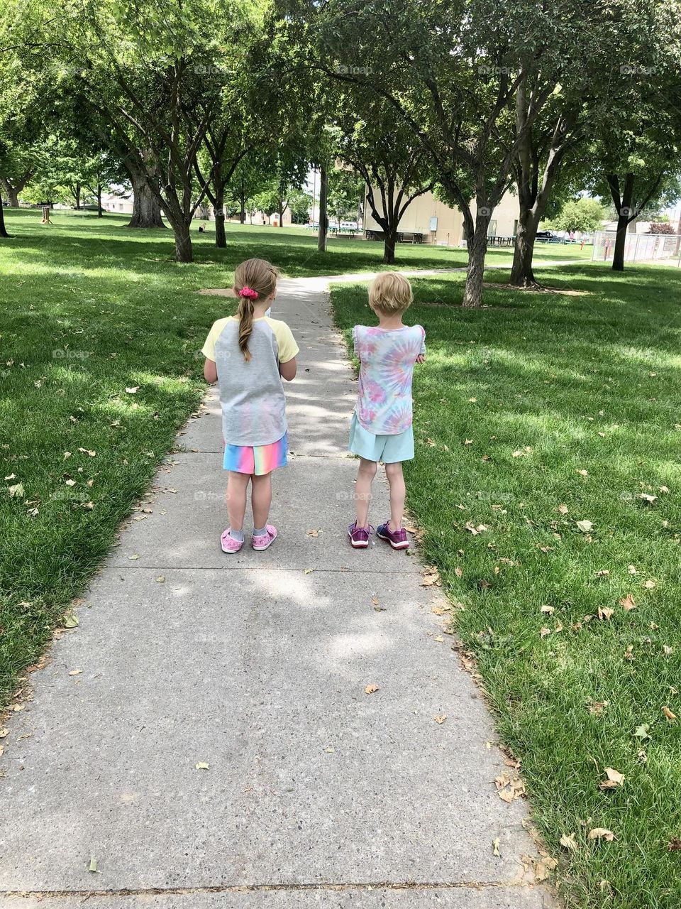 Little girls walking a path in a public park 
