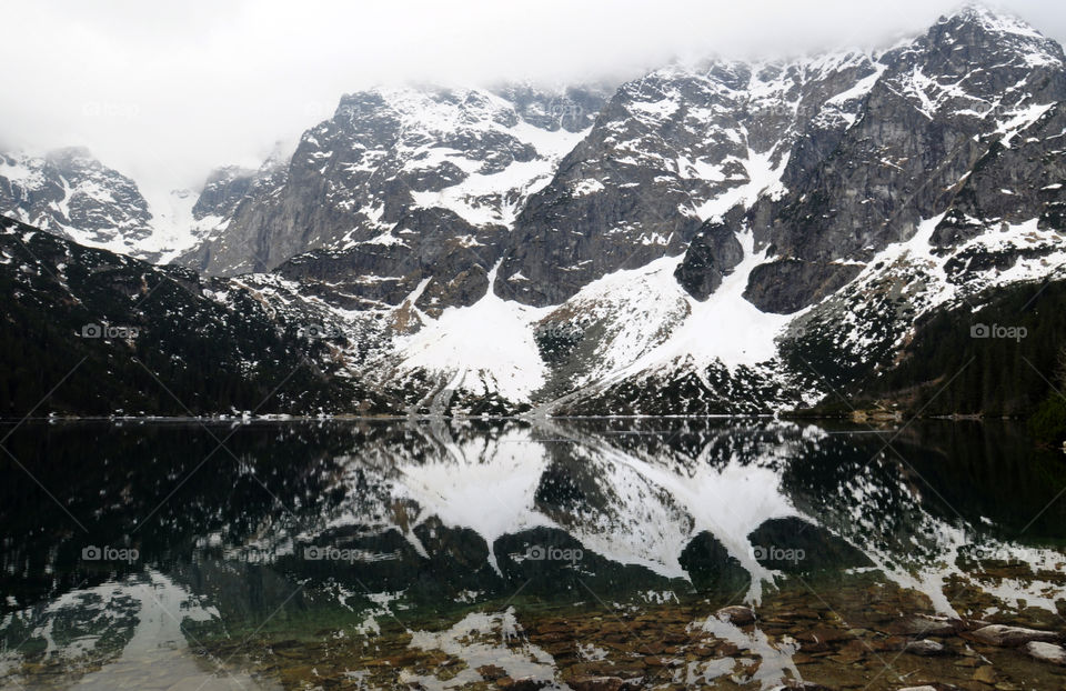 Snowy mountains reflecting on lake