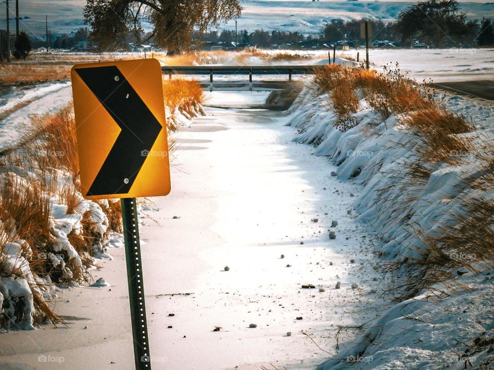 Empty ditch reservoir and caution turn sign.