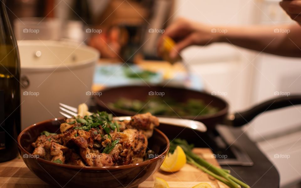 Cooking dinner at home side view of food in bowl and pots on stove with woman squeezing lemon over pan 