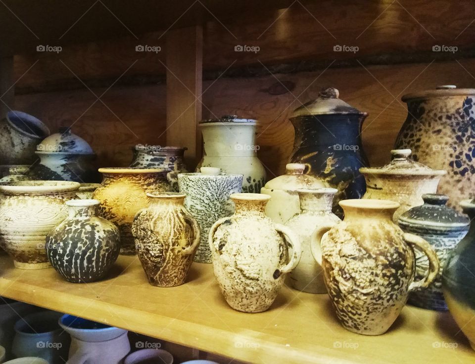 pottery is on a shelf in the village house. jars of clay.