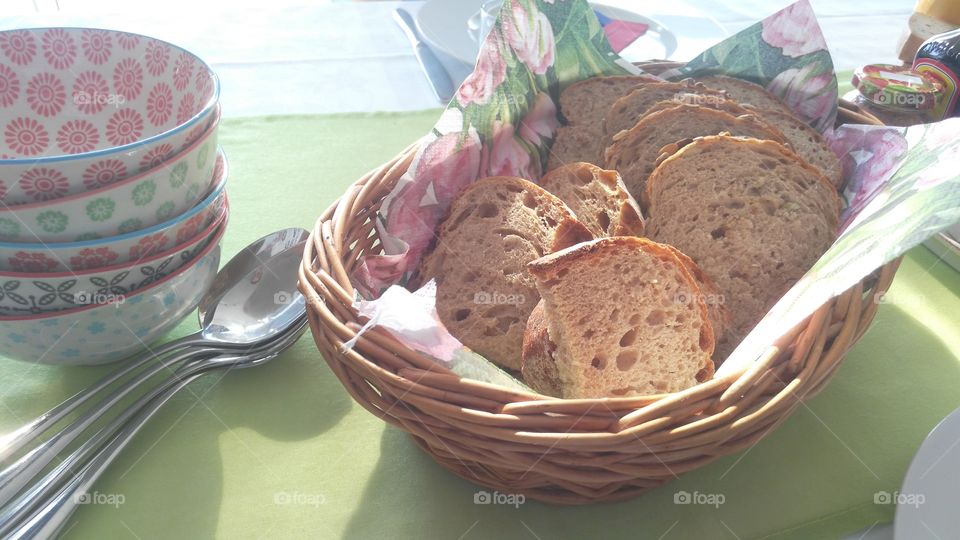 bread in a basket with teaspoons and bowl on a table, eat breakfast in the morning