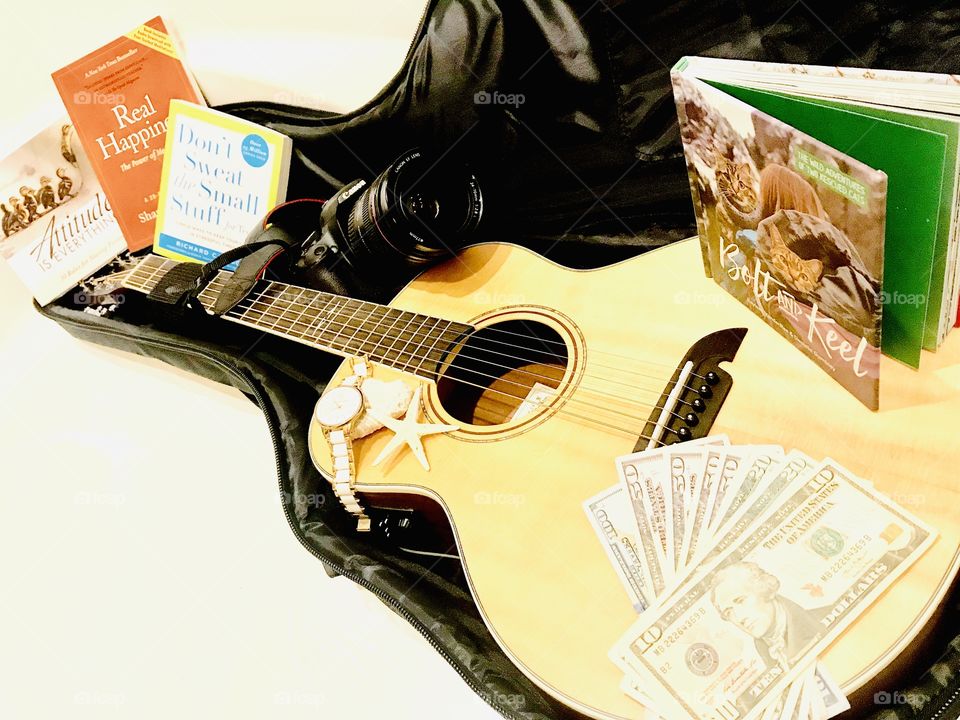 Fun photo of guitar with guitar case filled with books, money, and camera for trip! 