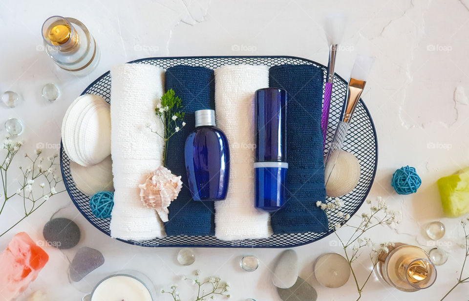 White table with spread out items for care and beauty: creams, brushes, towels with spring flowers. The first sign of spring: women are beginning to actively tidy themselves up and take care of themselves