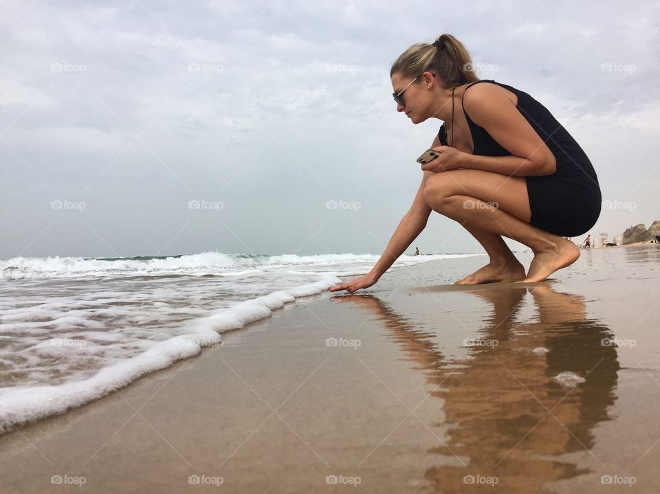Young woman holding mobile phone in hand near seashore