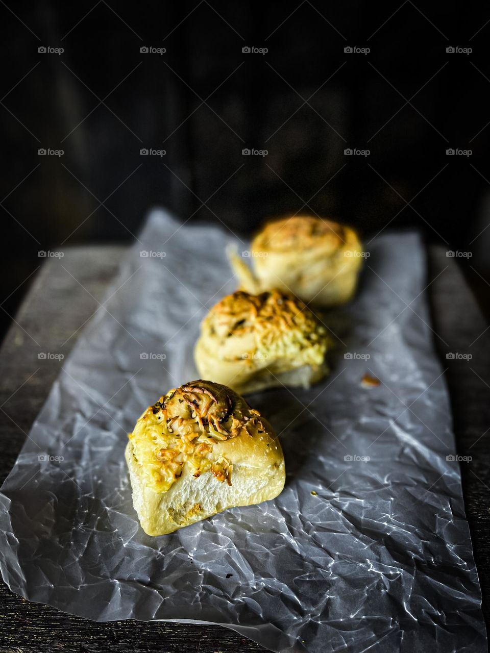 A delicious cheese buns on a baking paper with dark background