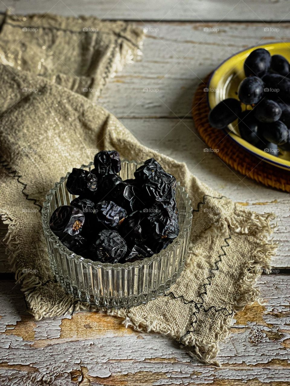 Bowl of dried dates and a linen cloth on a wooden background.