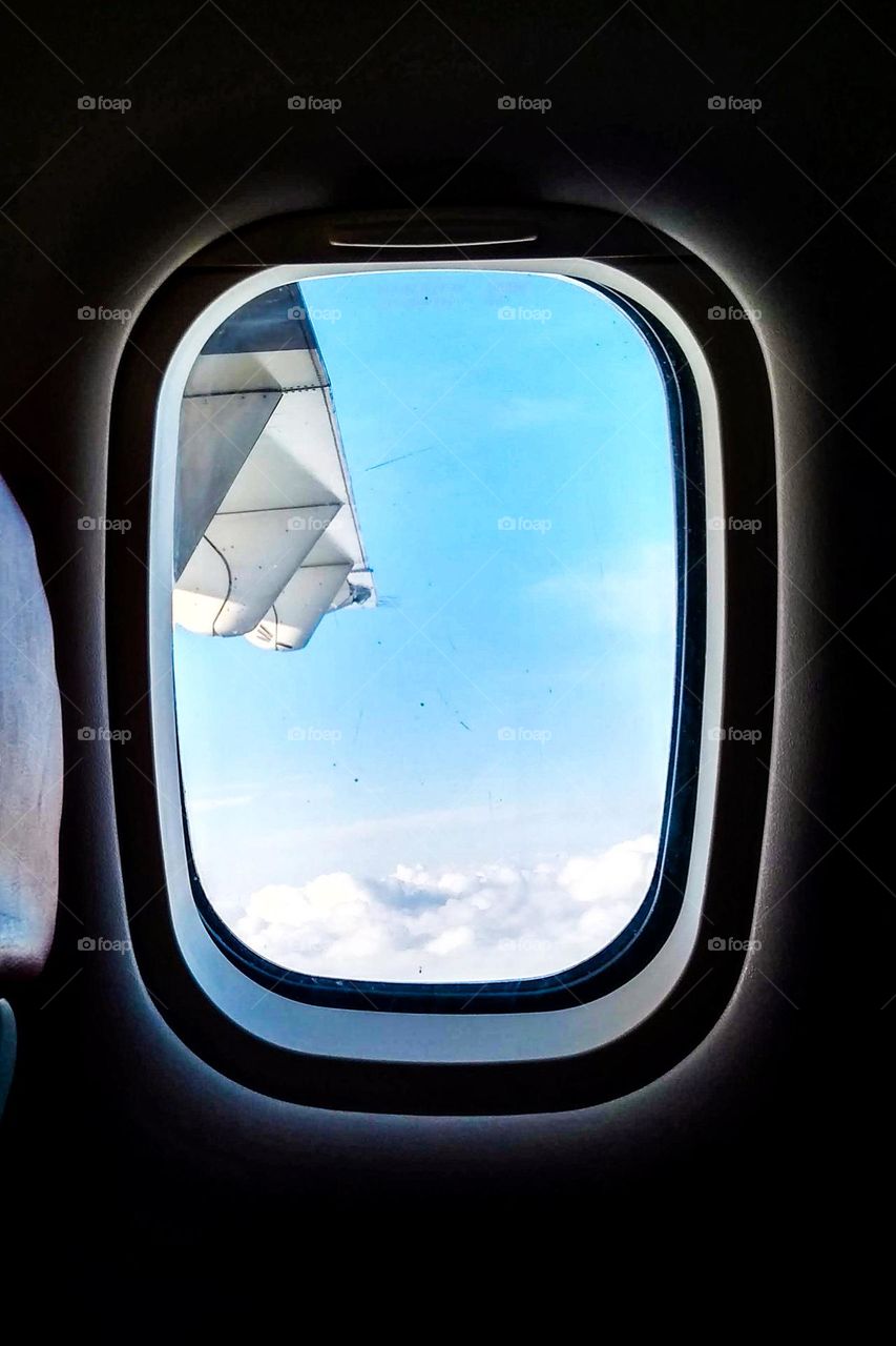 Flying above the clouds seen from inside the aircraft cabin in eye level view