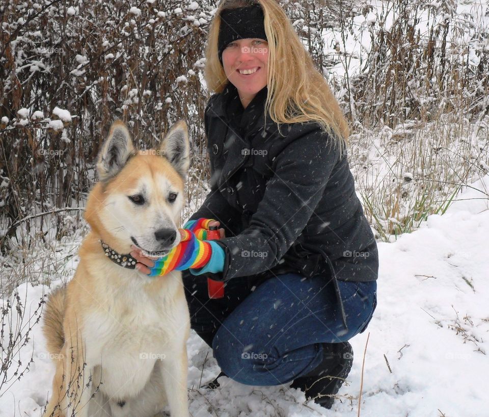 Happy woman crouching with dog during winter