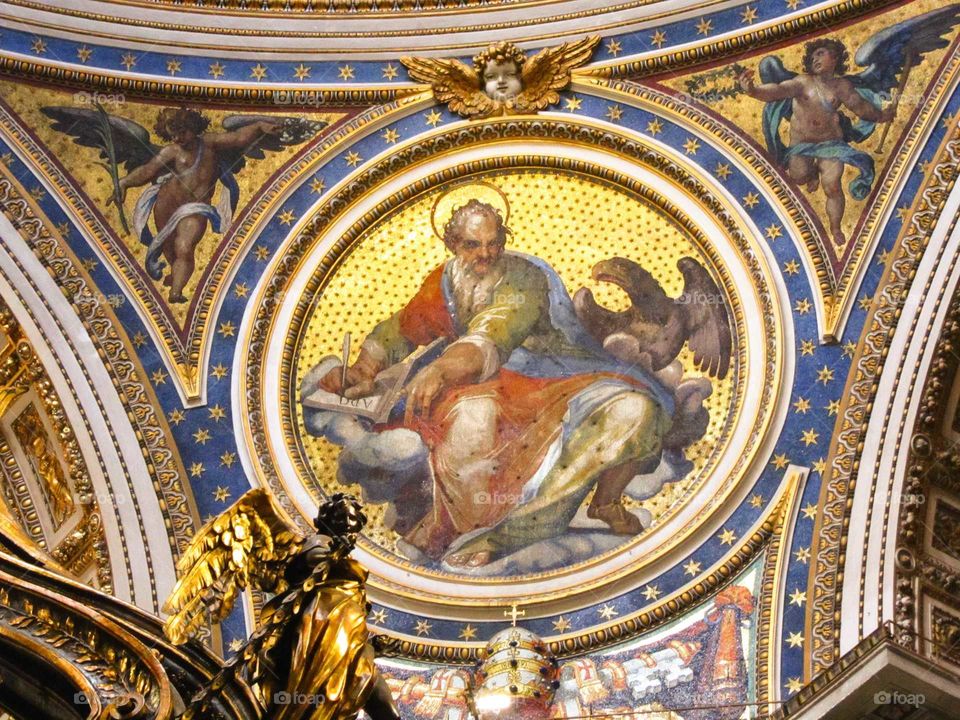 a beautiful blue, red, and gold leaf fresco showing a saint surrounded with gold stars and an angel with gold wings in the Vatican in Rome, Italy