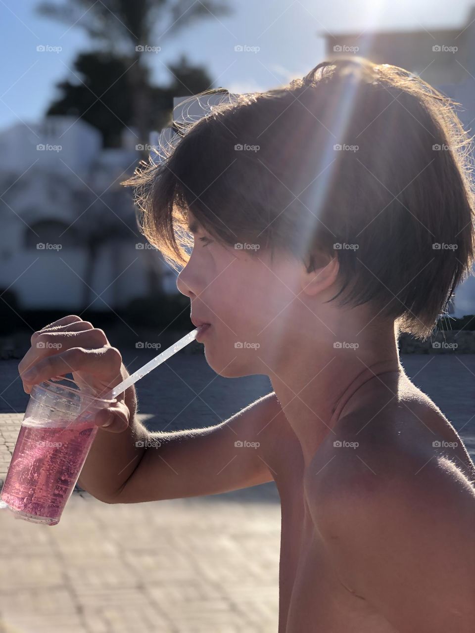 Handsome boy drink lemon near the sea