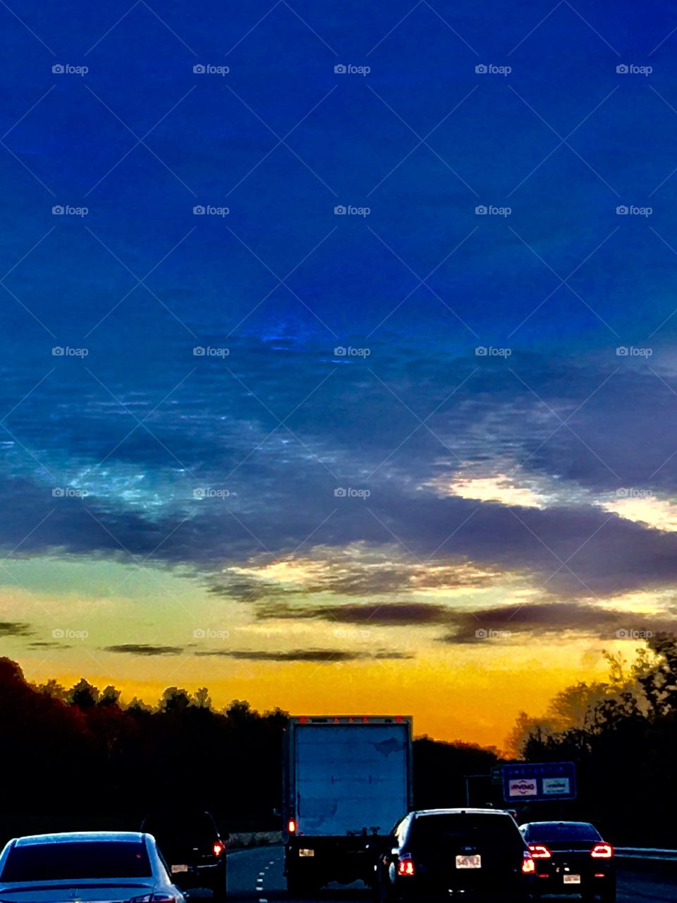 Sunrises & Sunsets of the USA! Roadtrip view of sunset/sunrise from highway traffic that's backlit from the low sun lighting the clouds in a beautiful display of colors.