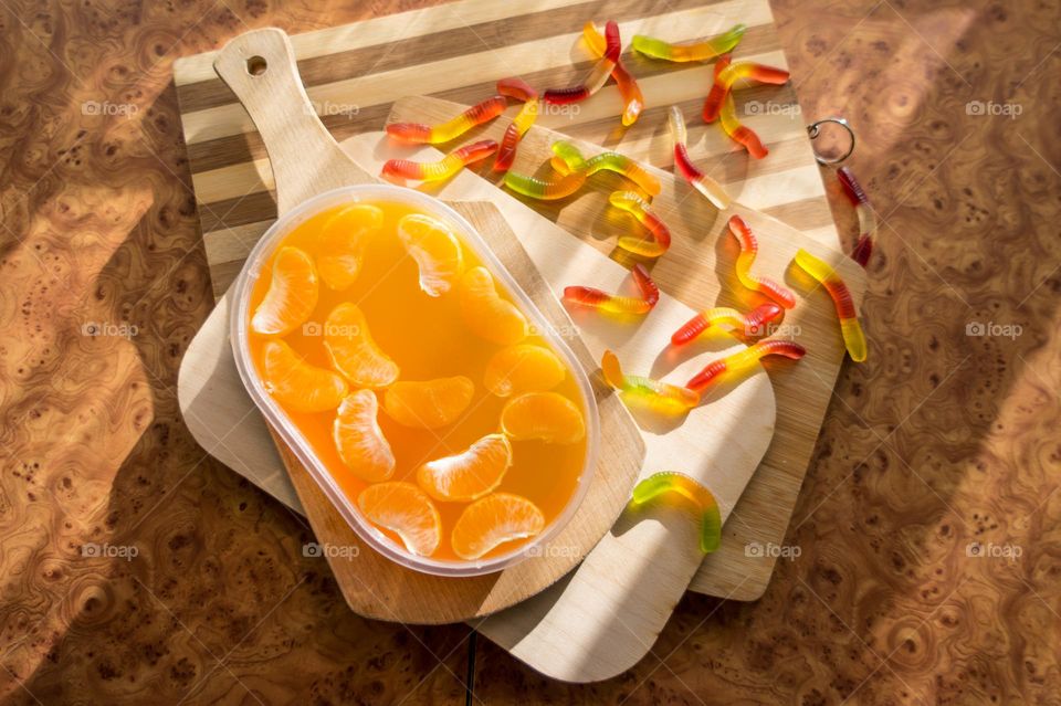 Delicious orange jelly with tangerine slices in a container and jelly worms.