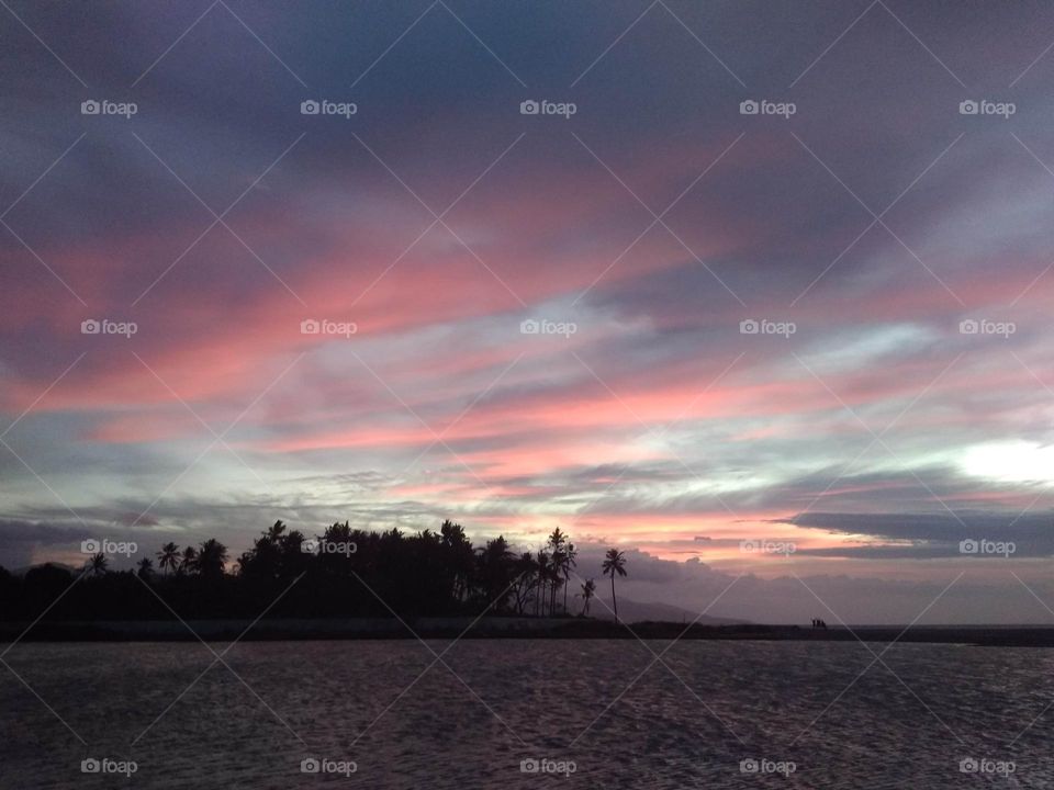 Pink sunset sky after a rainy day by a river and beach