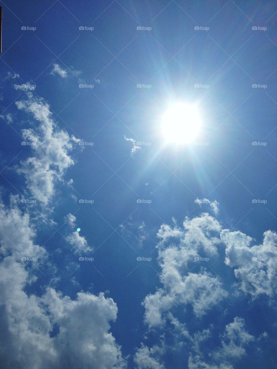 Sun with clouds against blue sky