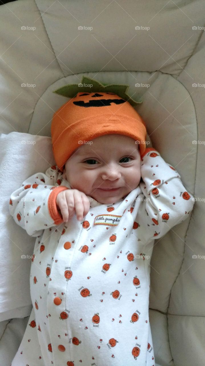 Smiling Baby wearing pumpkin pajamas