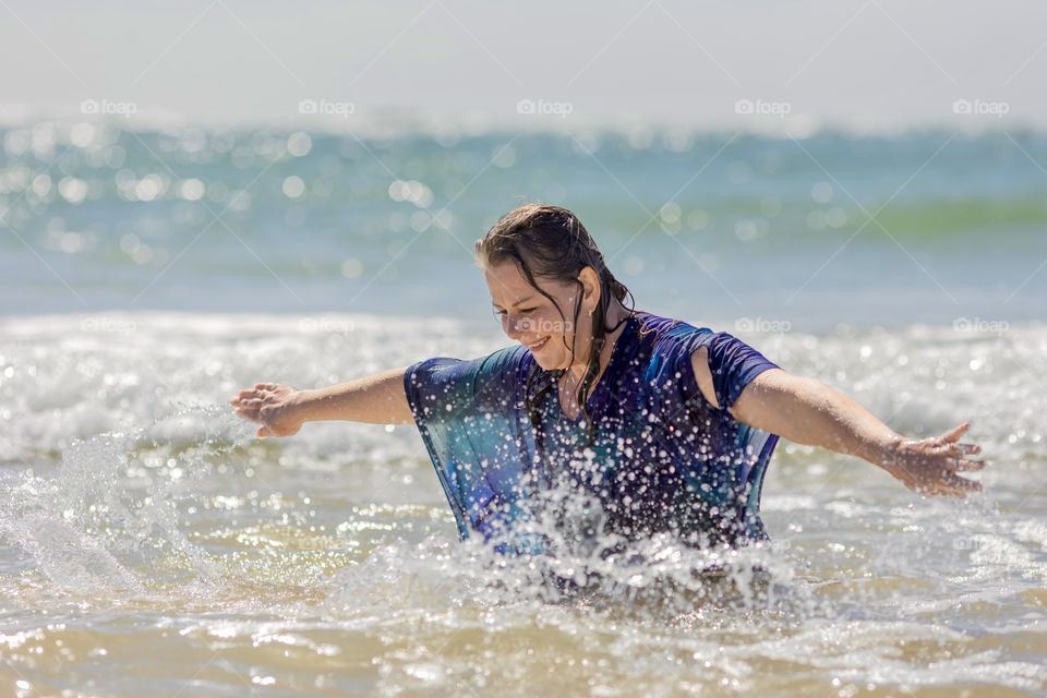 Woman has fun in the water on the beach 