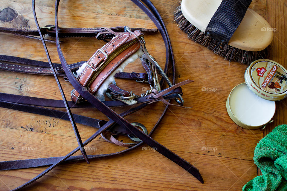 Horse tack on a wooden work table in a stable