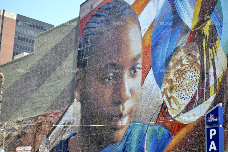 A colorful mural of a young boy painted on a city wall made of concrete blocks