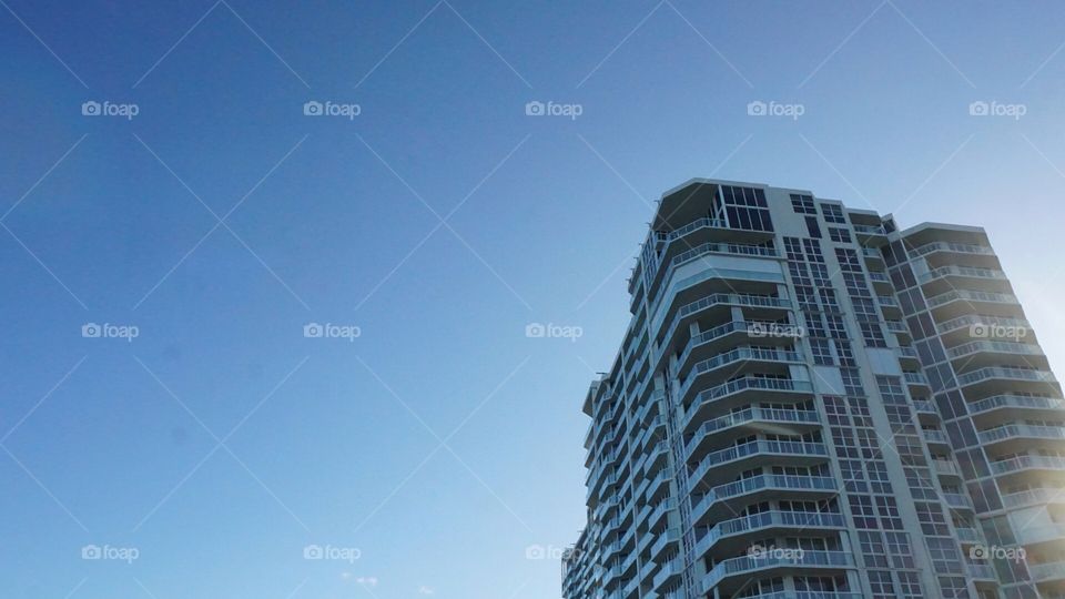A tall commercial building on a beautiful location in front of a peaceful blue sky.
