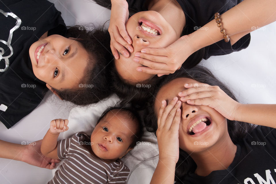 Elevated view of girls with eyes closed and baby lying on bed