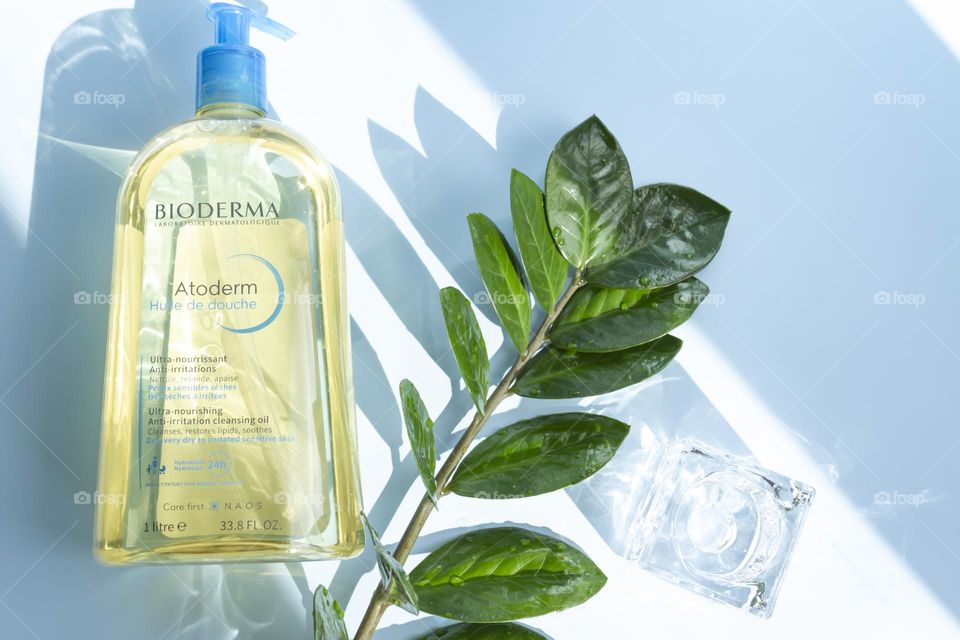 Cosmetic product Bioderma for skin care on a blue background, with a green flower.