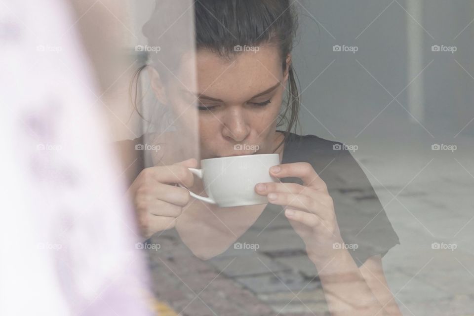Girl enjoying a coffee break ... photo taken through a window 
