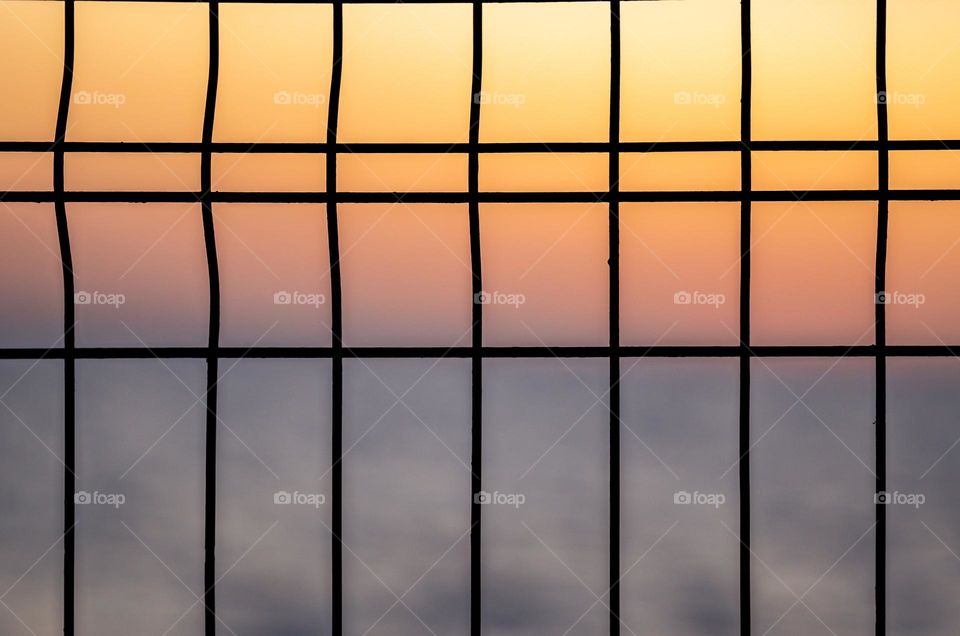 Sunset behind a metal fence