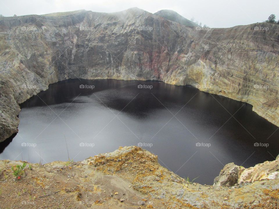 Lake Kelimutu with its black water color. The walls of the lake are naturally formed from mountain rocks.