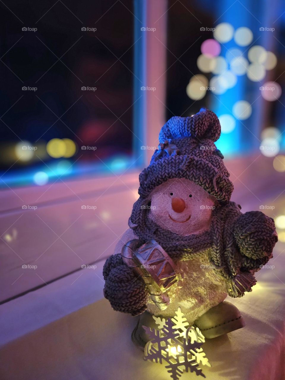 Wintertime- snowman figure on the windowsill with Christmas lights