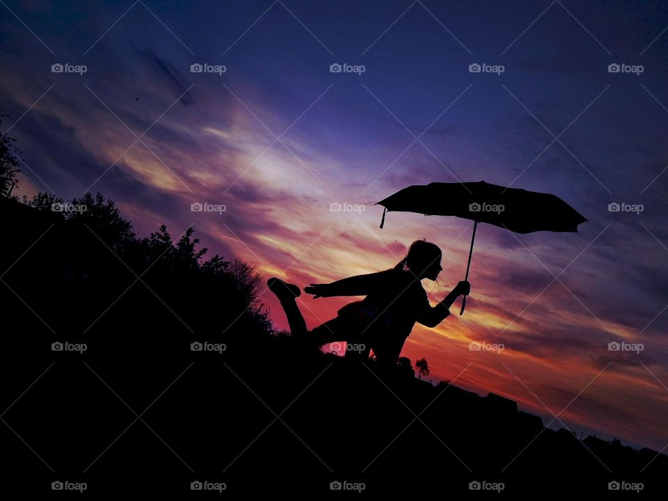 Girl with umbrella on sunset background