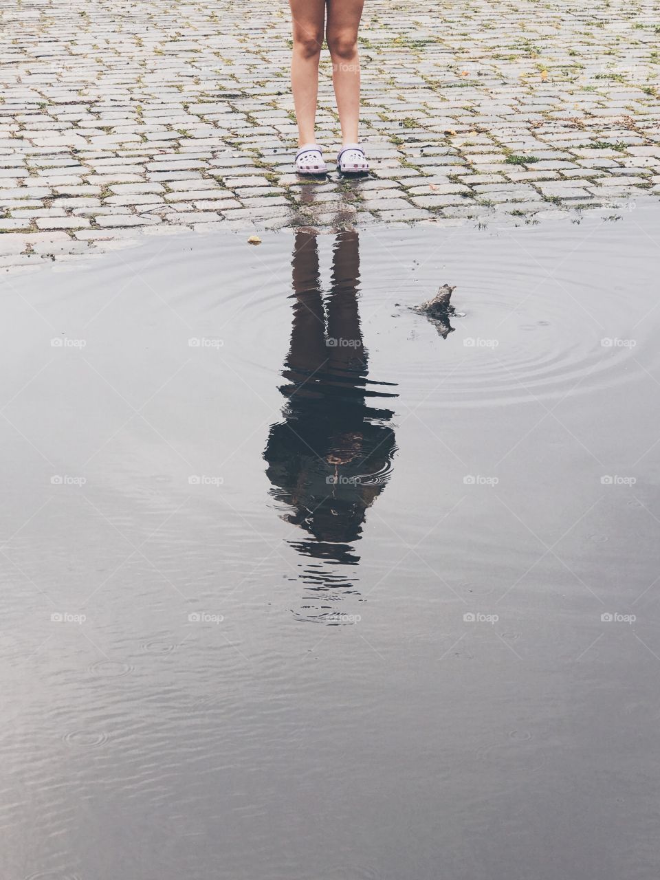 Reflection of a child in the water pond  throwing a stone in the water