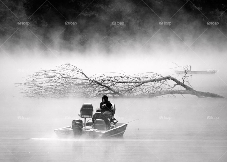 Boating in the fog. Changes in temperature create a thick fog on the surface if the pond, but that didn't stop this man and child from going out in the boat for a ride..... but that tree debris might. Look out guys!
