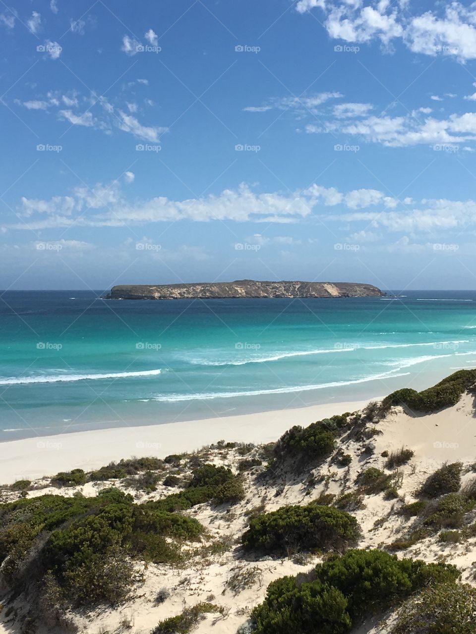 Cliffs on an island in the distance forms gorgeous backdrop for this remote and beautiful turquoise water and white sand beach in southern Australia 