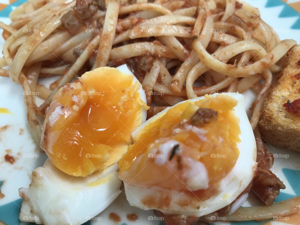 Spaghetti with ground beef and tomato sauce with boiled eggs and toast servers on a plate