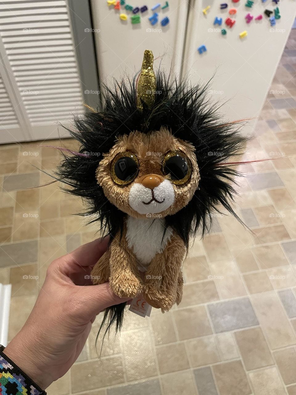 Woman’s hand holding a lion stuffed unicorn, lion unicorn, cute stuffed animals for kids, woman’s hand holding toys for her child, mommy holds toy for toddler