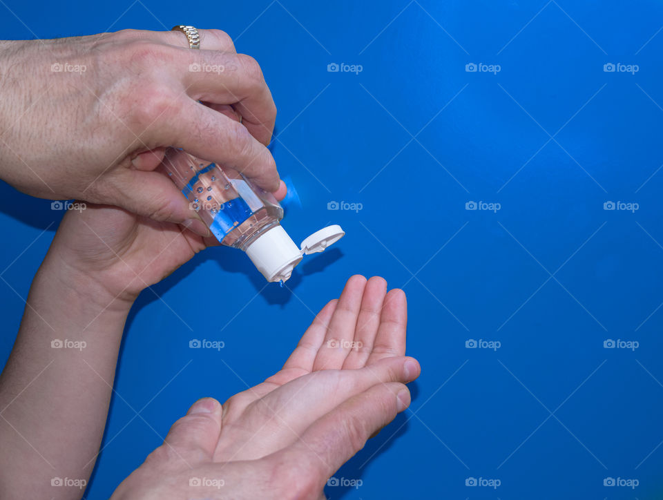 Young hands use a hand sanitizer on a blue background