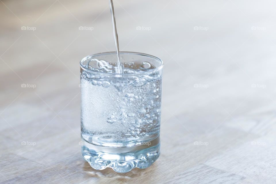 Pouring up a glass of water on a wooden table 