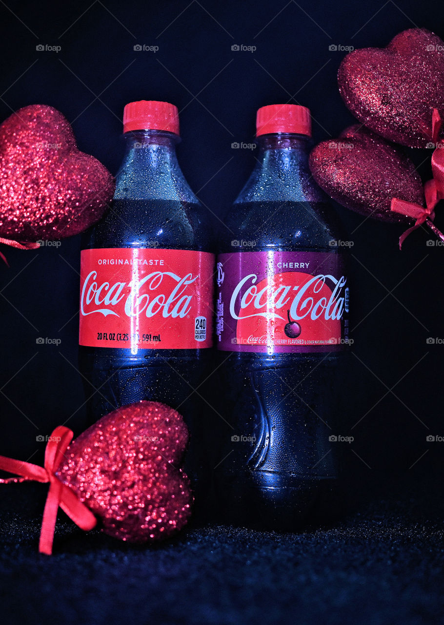 Close up shot of coke cola with valentine hearts in a black background in studio.