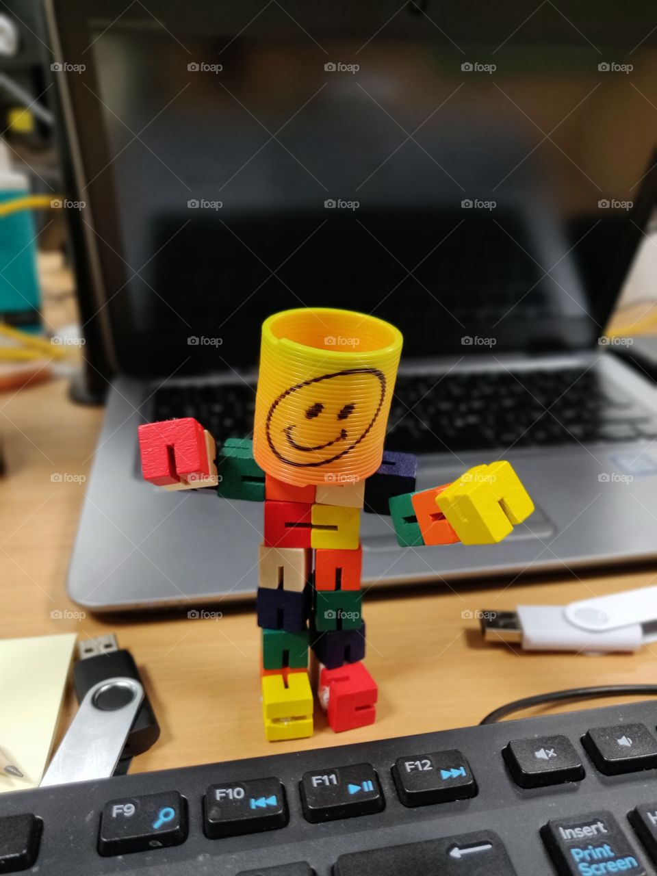 Smiley emoji man on the office desk by the laptop and keyboard
