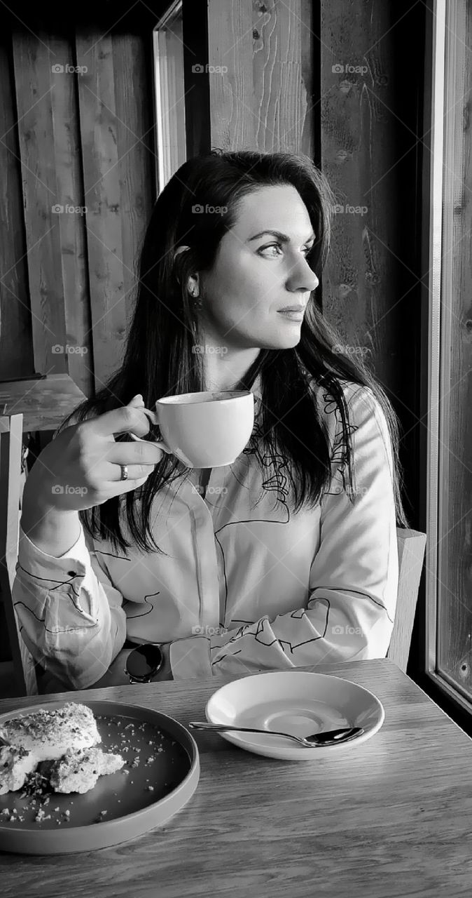 Woman sitting with a cup of coffee in a cafe and looking out the window