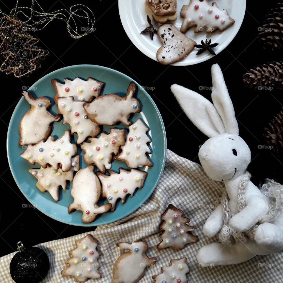 Home made Christmas cookies on black table and white rabbit