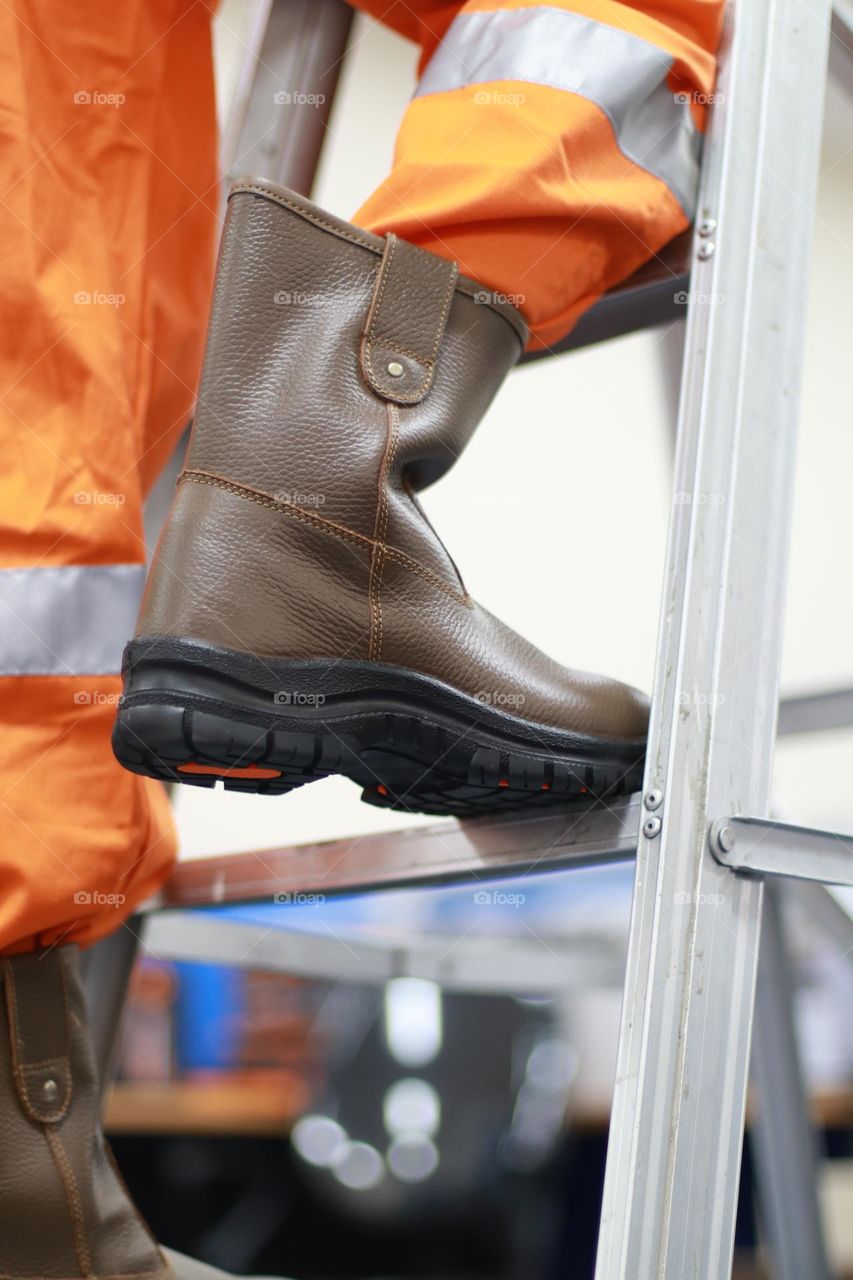 Photo of workers wearing safety clothes and safety boots climbing stairs to fix something