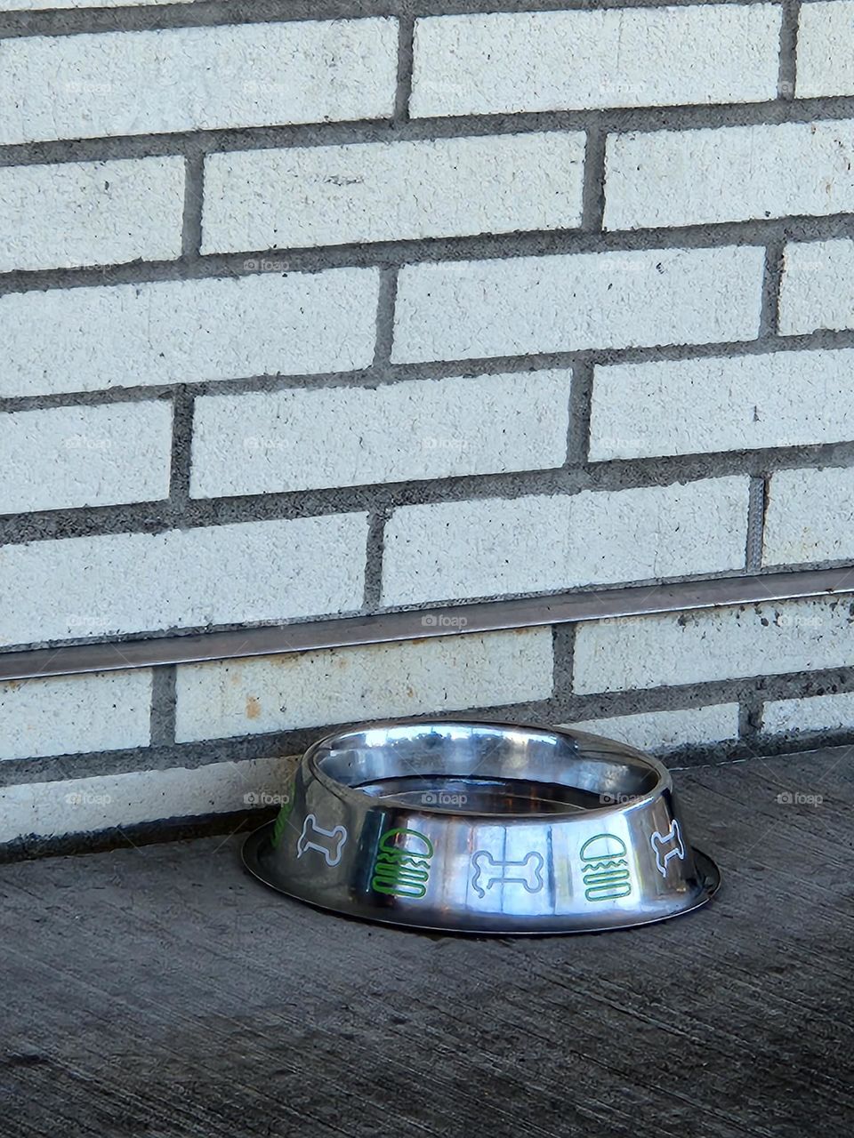 metal water dish for dogs against brick wall of restaurant