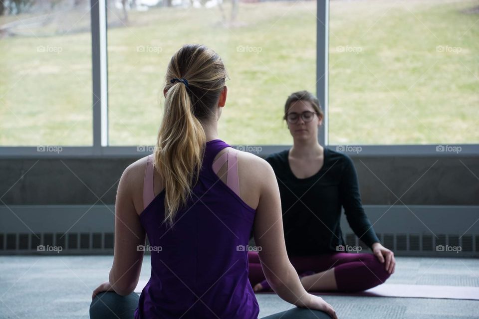 Young woman teaches a yoga session while looking out to a beautiful landscape of mountains 