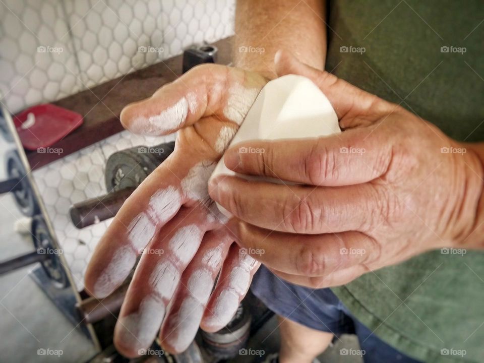 Man chalking his hands to lift free weights to stay fit