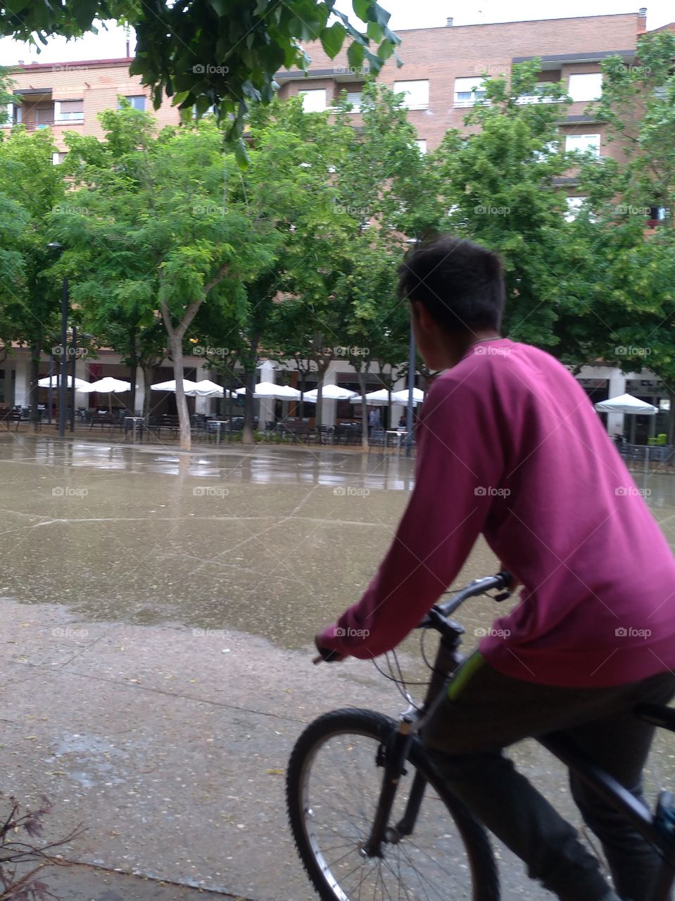 Un joven pasa con su bicicleta por una plaza