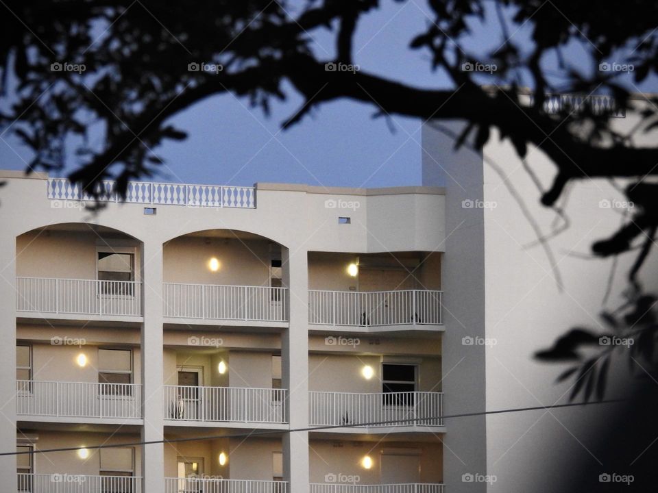 Apartments complex building in central easter Florida close-up in the evening before night falls with a tree branch in the foreground and lights on.