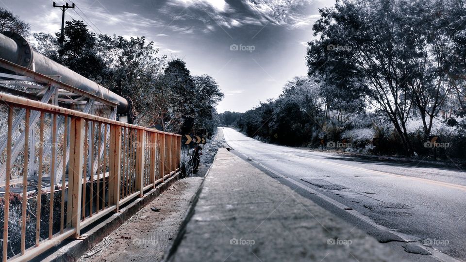 Efeito bonito sobre a rodovia, as árvores, o céu, e o corrimão.